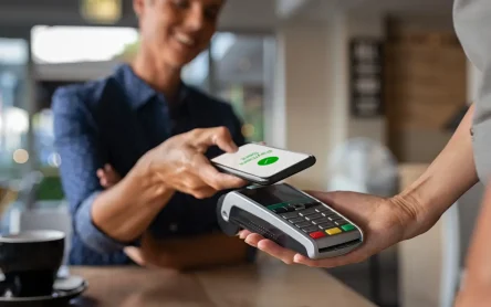 Customer completing a Contactless Payment at a store using a smartphone and a payment terminal.